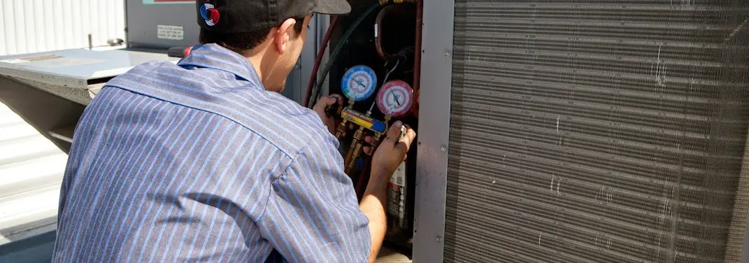 HVAC technician servicing a condenser unit in Northlake
